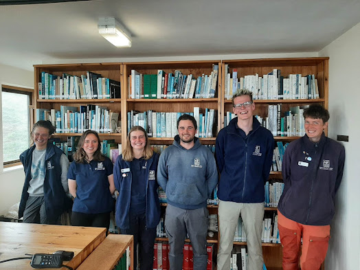 The Skomer Island team standing in front of a book case. Left to right, we have Hannah, Lotti, Erin, Leighton, Rob and Ceris.