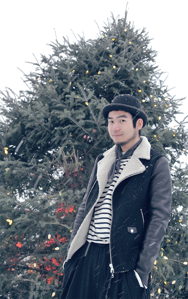 Man in black leather wool Mackage jacket coat with cut wool collar, wearing black bowler hat in front of Christmas Tree, at Montreal Jardin Botainique near Olympic Park