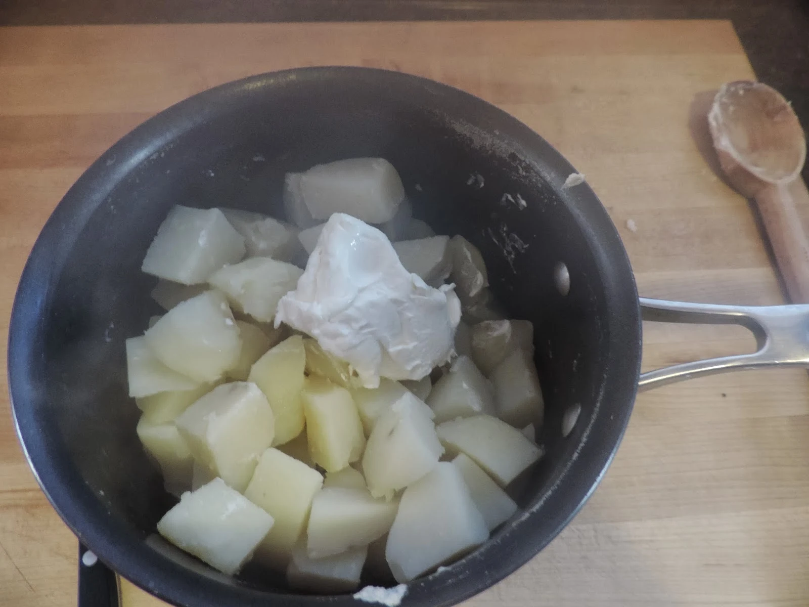 Cream Cheese being added to the cooked potatoes.