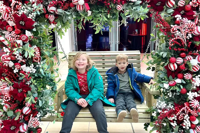 happy children on a bench surrounded by christmas decorations in The Harvey Centre, Harlow