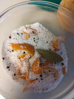 A mix of citrus peel and whole spices in a bowl of sugar