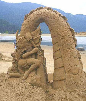 Escultura simula um dragão que brota das areias da praia e engole o escultor.