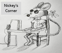 Nickey, one of the blind mice, is seated at a table in Nickey's Corner with his front paws on a computer keyboard.  He is wearing shorts and a short sleeved shirt with a bowtie and sunglasses. The tip of his tail is bandaged.