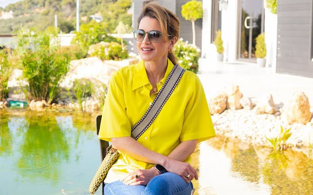 Queen Rania carried a Tissa Fontaneda Rock Me crossbody bag. The Queen wore a yellow silk shirt and blue denim pants