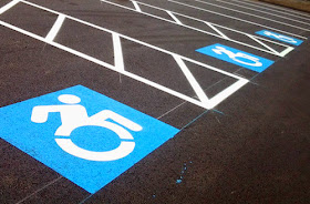 Color photo of three accessible parking spaces featuring the new wheelchair symbol design