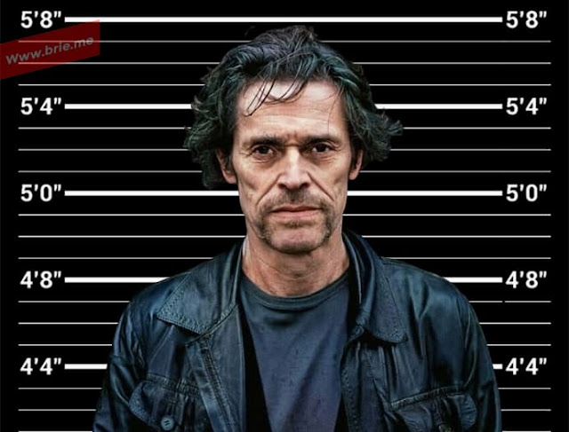 Willem Dafoe standing in front of a height chart