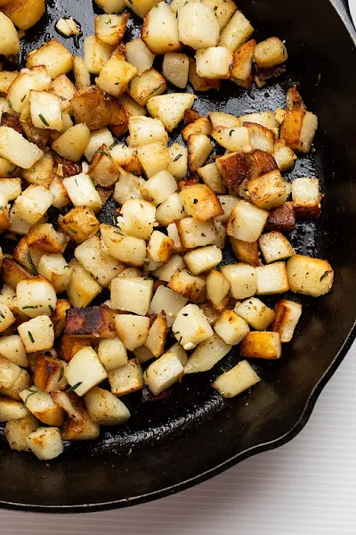 Top view of country fried potatoes in a cast iron skillet.