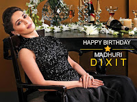 madhuri dixit, bollywood most famous and talented actress sitting on chair in black designer dress along table with the wine bottle and glass with some flowers