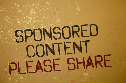 brownish background with the words engraved on reading "sponsered content, please share" in black and red writing