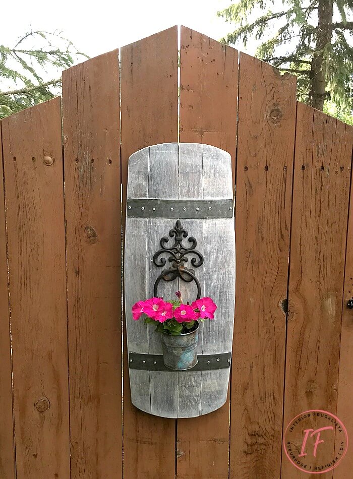 A unique barrel stave outdoor wall planter idea using a repurposed stave and wrought iron door knocker for a one-of-a-kind hanging flower planter.