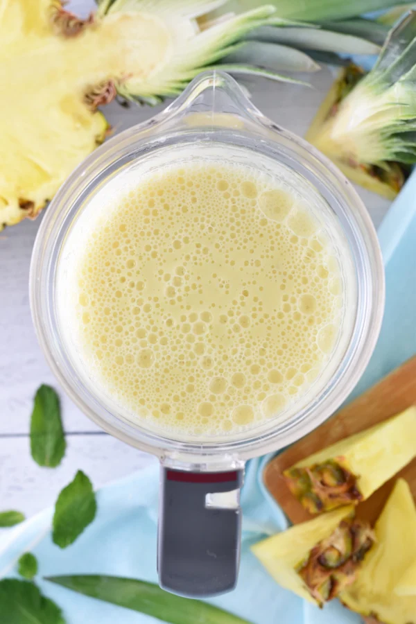 Creamy pineapple banana smoothie ready to serve in a blender viewed from above.