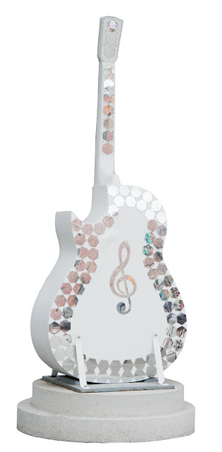 Orillia outdoor art display in downtown, guitars with paintings on them, this one is white with mirrored tiles and a treble clef in the middle