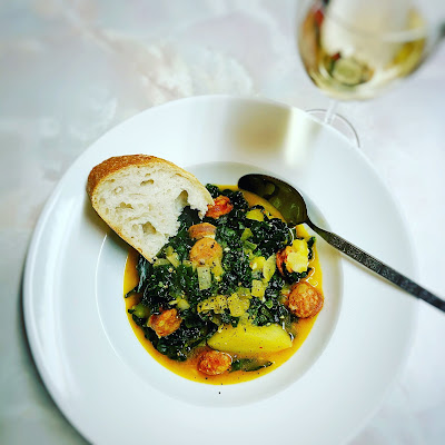 Caldo verde in a dish with a spoon and a glass of sherry