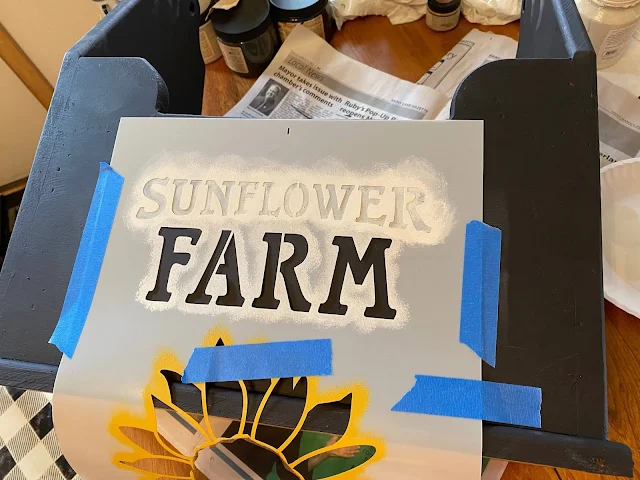 Photo of Sunflower Farm stencil from Old Sign Stencils being taped onto a painted tool caddy.