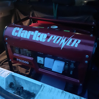 Clarke Power, a red generator machine, fills the boot of a small white car.