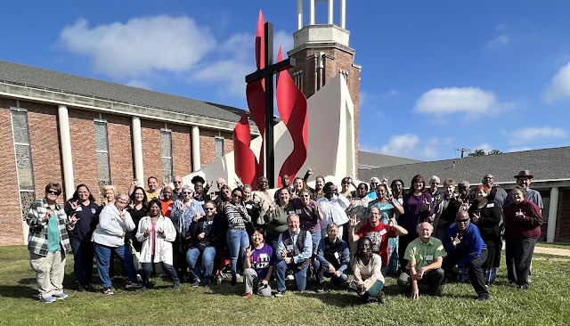 a large group poses in front of a church