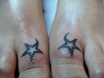 Two small tribal star tattoos on the foot thumbs.