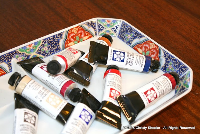 A closer view of the watercolor tubes resting on a decorative tray.