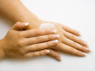 A woman with dry and wrinkled hands applying a cream