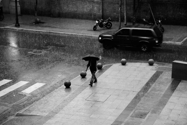 Un hombre bajo un paraguas en plena lluvia,en Blanco y Negro.