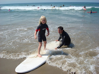 Aloha Beach Camp surf camp instructor Scott Kelly teaches a young child how to surf at summer camp.