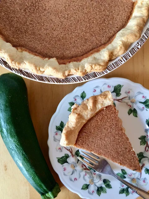 Photo of finished zucchini pie with a slice on a small plate.