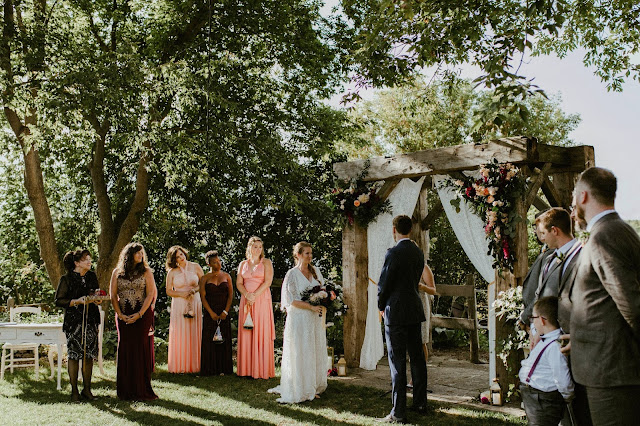 wedding arch with wedding party in front boho romantic styling