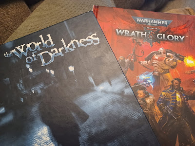 photo of two hardcover RPG books-- the black and blue World of Darkness and the bold red of Wrath & Glory