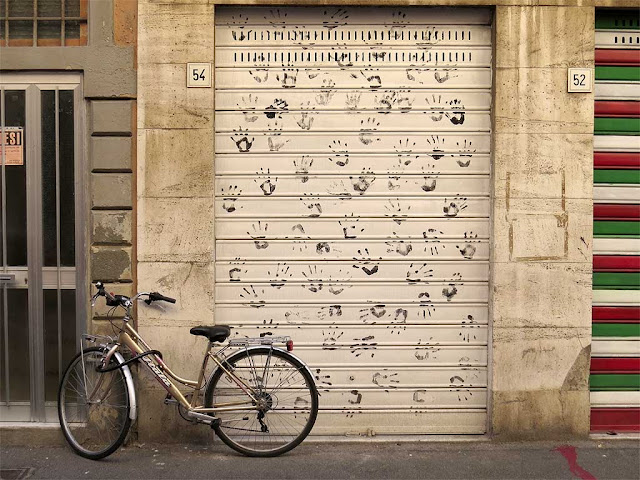 Mani nere su di una  saracinesca, via della Posta, Livorno