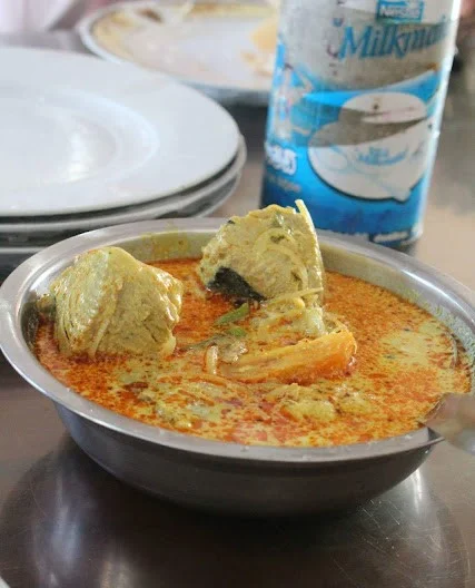A small silver bowl of Sri Lankan coconut milk and spices fish curry with fish pieces.