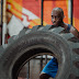 Man in blue tank top and shorts doing tire training exercise