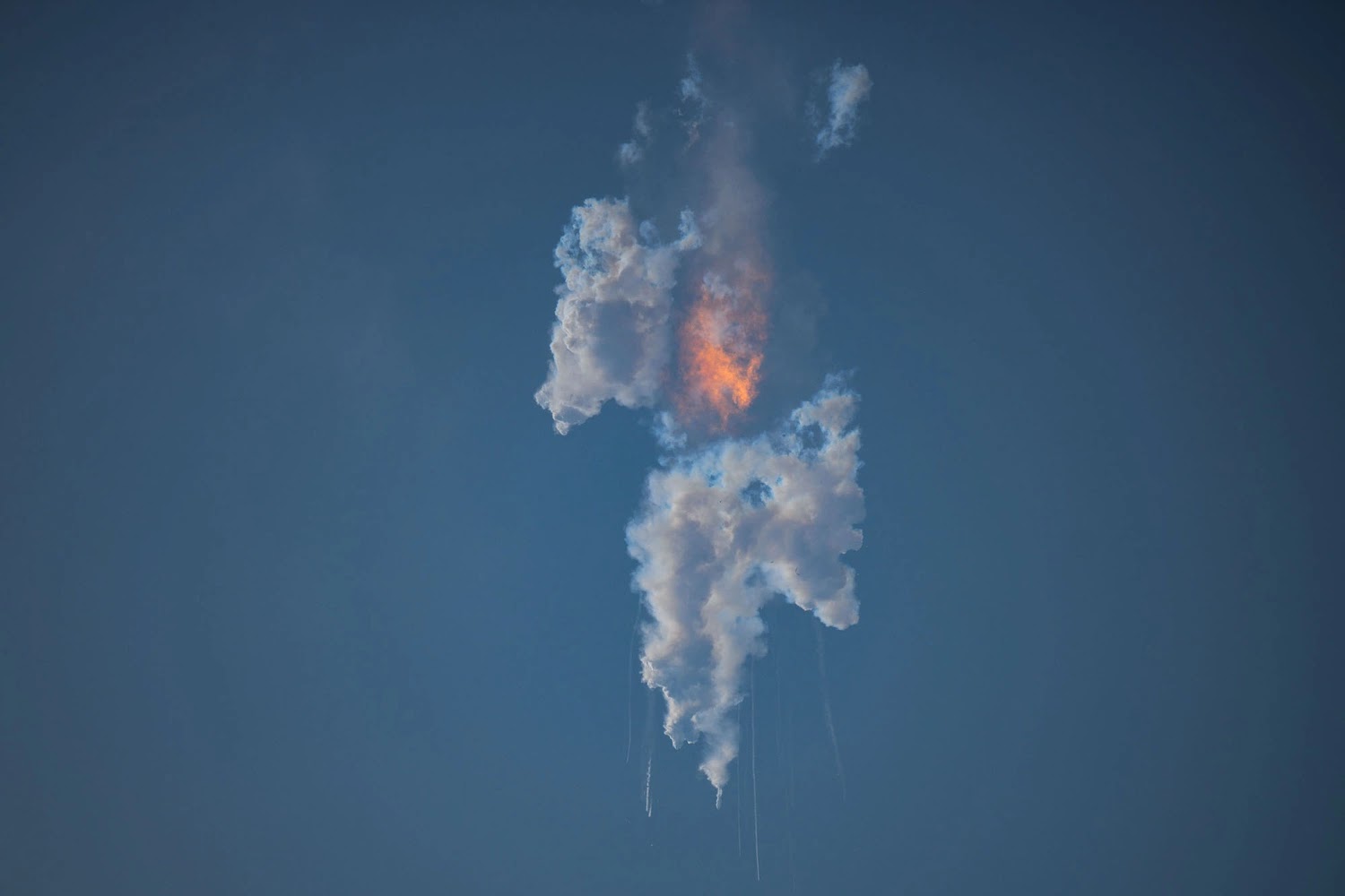 A view of white clouds and a fireball in the sky after the explosion of the SpaceX Starship rocket