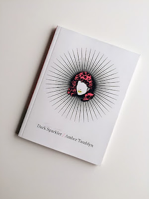 A white background with a stencil of a woman's head inside a star. She has pink hair and yellow lips. The text reads 'Dark Sparkler' 'Amber Tamblyn'