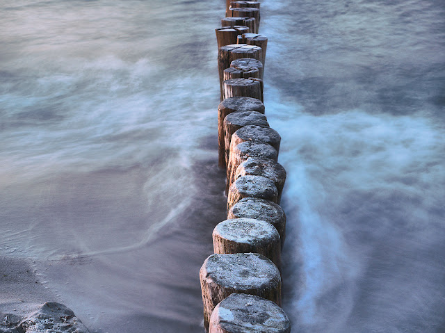 Holzpfähle im Meer brechen die Wellen.