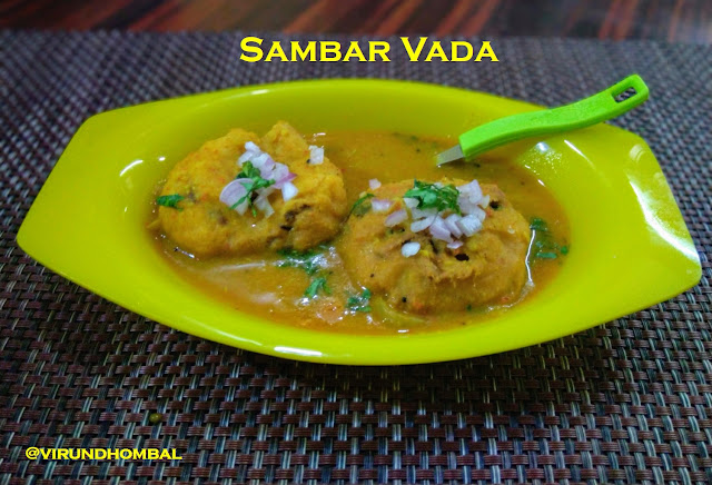 Sambar Vada -  easy and tasty  homemade sambar vada with simple cooking methods. The recipe for the sambar is same as the tiffin sambar recipe posted early this year. The only change in the tiffin sambar recipe is that I have added toor dal instead of moong dal because moong dal will be thick for sambar vada. The fried medhu vadas are soaked in the warm water for 10 minutes and then added in the hot sambar. The tiffin sambar can be made ahead of time and refrigerated. Just warm the sambar in a broad pan or kadai to soak the vadas. For vadas I have added few onions and green chillies. Just before serving, a handful of finely chopped onions are garnished on the top of the sambar vadas.