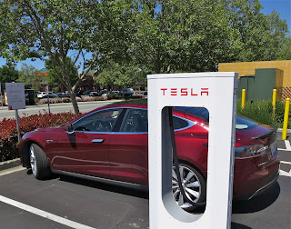 A red tesla model s charges at a tesla charging station