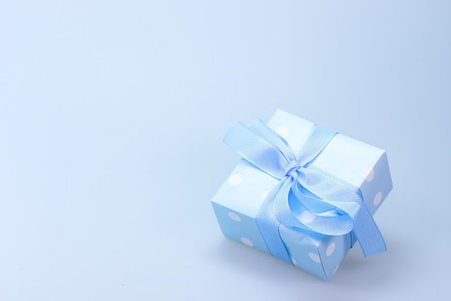 A gift wrapped in blue and white polka dotted wrapping paper with a blue bow