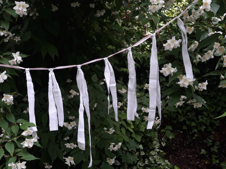 Girlande aus Stoffbändern als Dekoration für die DIY-Hochzeit oder Gartenparty