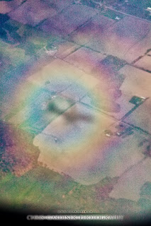 Airplane window seat photography by Chris Gardiner www.cgardiner.ca who tends to fly westjet a lot showing this strange optical phenomena of a full circle rainbow projected on the ground with the plane's silhouette inside of it. 