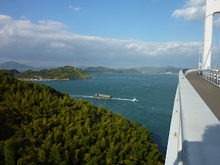 Looking back towards Oshima from the shikoku side of the Kurushima-Kaikyo bridge on the Shimanami Kaido Bikeway. There's a tug boat pulling a container ship in the seto sea