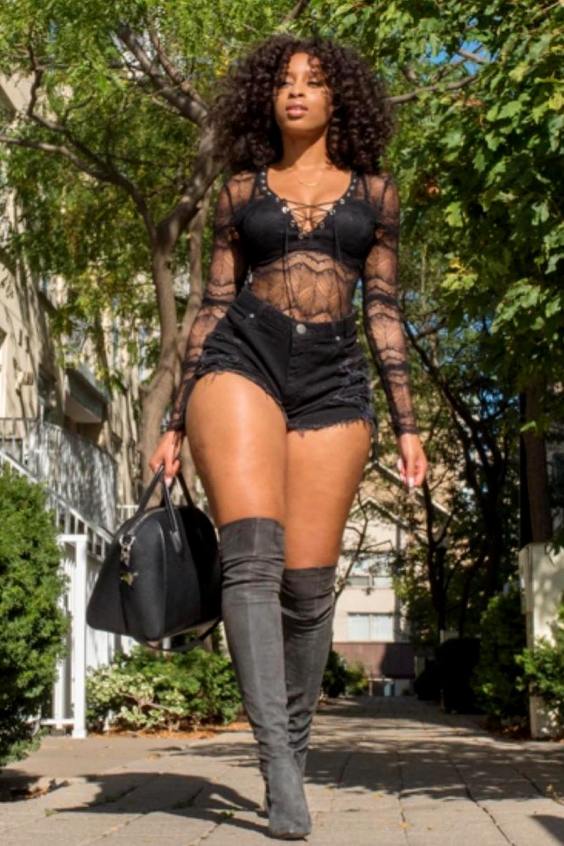 Woman wearing a transparent top, black shorts and gray over the knee boots
