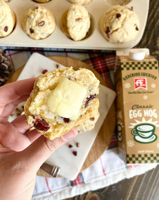 Hand holding half of an cranberry egg nog muffin with butter.