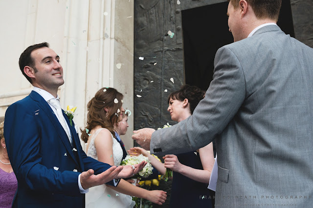 Guests throw confetti at bride and groom