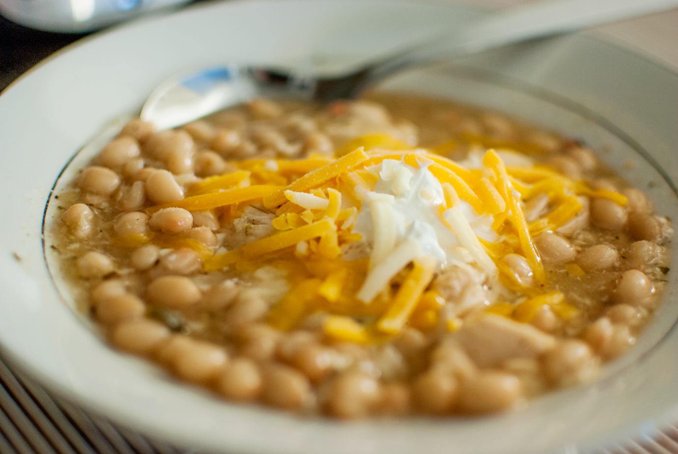 Bowl of White Bean Chicken Chili With Sour Cream and Shredded Cheese