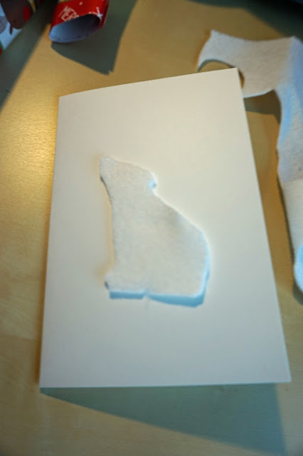 A glued on white felt cut out Polar Bear, on a white blank greetings card