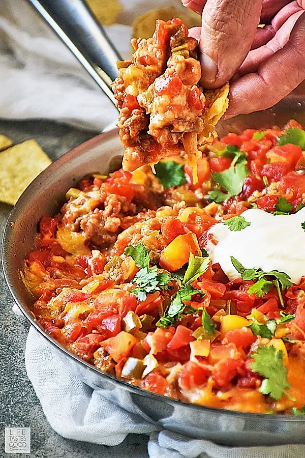 Chip dipped into the Hot Mexican Dip with sausage, beans, cheese, and tomatoes