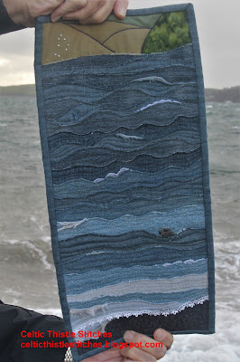 Hands holding a seascape art quilt