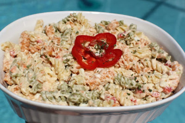 This is tri colored spiral pasta made into a macaroni salad with tuna in a glass white casserole dish