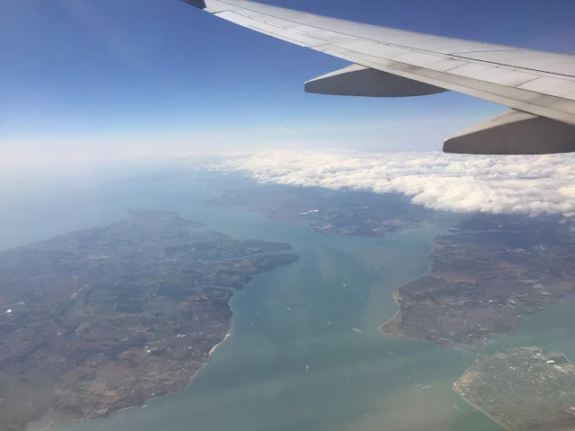 View out of an aeroplane window towards islands and sea and blue sky