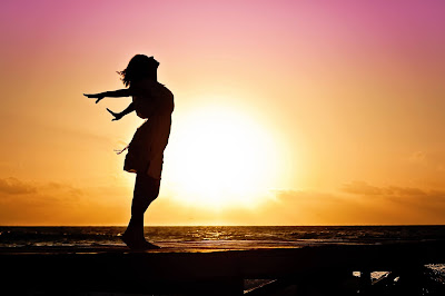 woman with arms stretched out facing wind